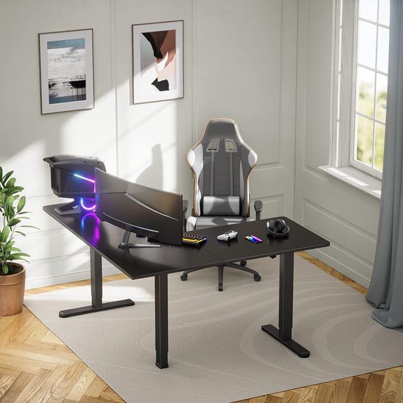 Spacious, sturdy, electric standing corner desk with three legs holding a monitor, computer and peripherals.